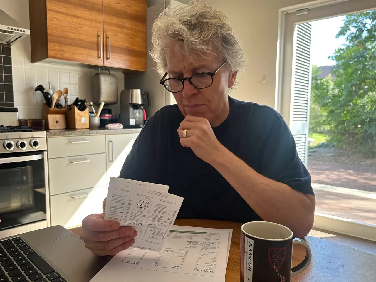 Homeowner at a kitchen table reviewing an energy bill and comparing heating costs
