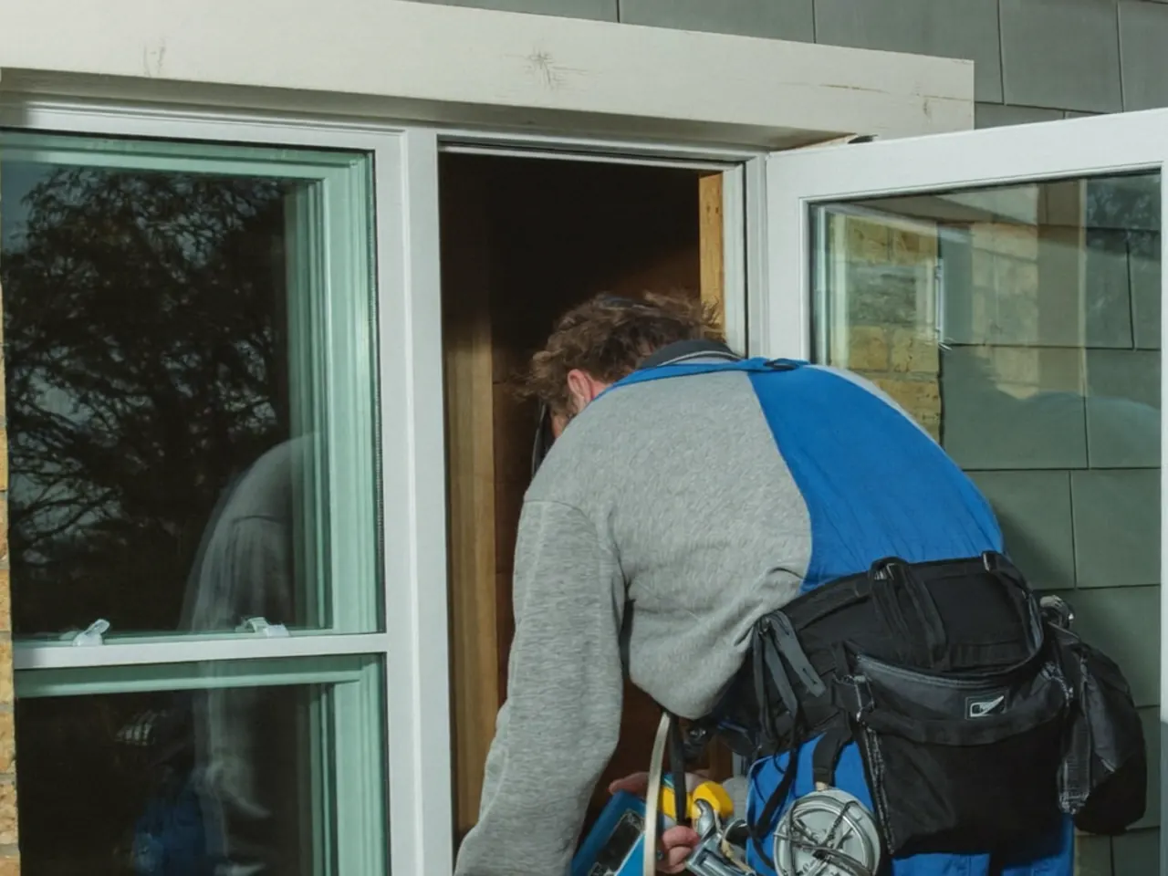Two installers carefully lifting a heavy triple-glazed window unit into position