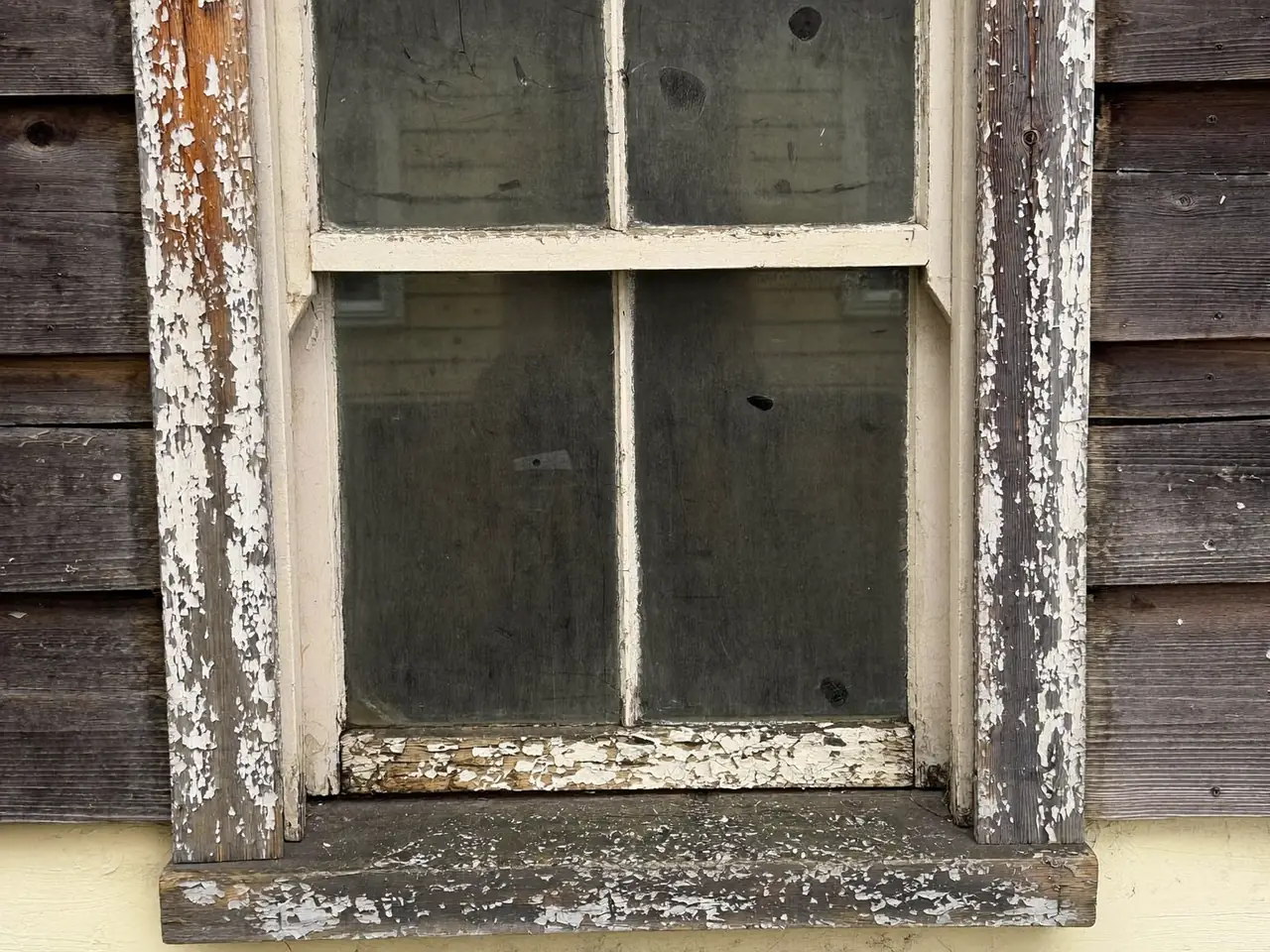 Old timber window with peeling paint and a failing frame that is due for replacement