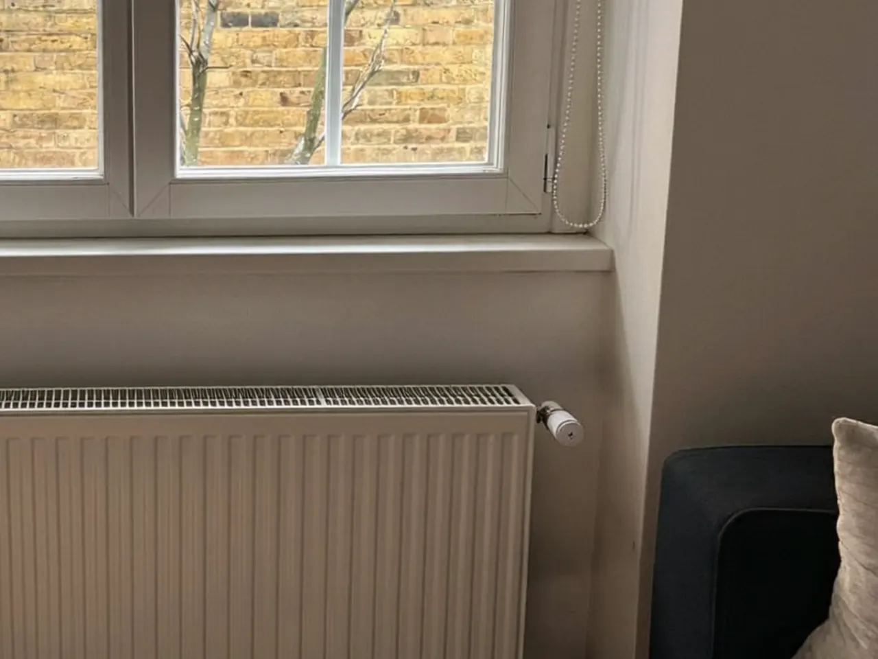 Room thermostat turned down beside a warm radiator in an energy-efficient home